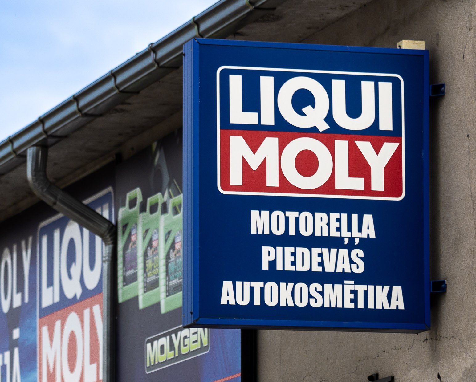 Zila LIQUI MOLY skatloga reklāmas izkārtne pie ēkas fasādes